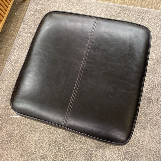 Black leather ottoman on a patterned carpet