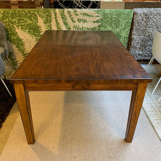 Wooden dining table in a room with patterned rug and chairs