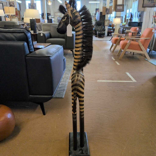 Wooden zebra statue in a furniture store with chairs and tables in the background