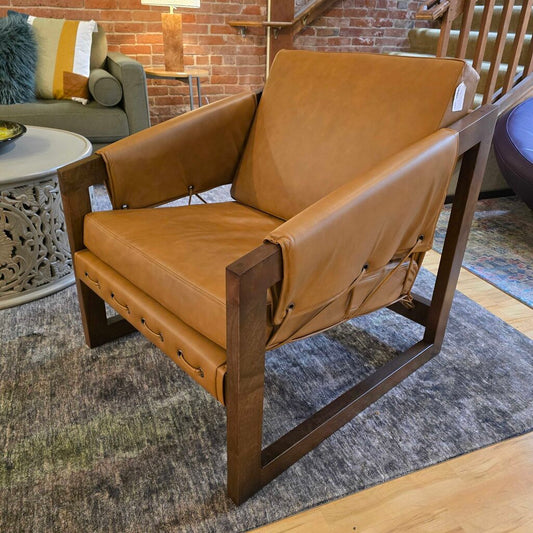 Brown leather chair in a room with a brick wall and other furniture.