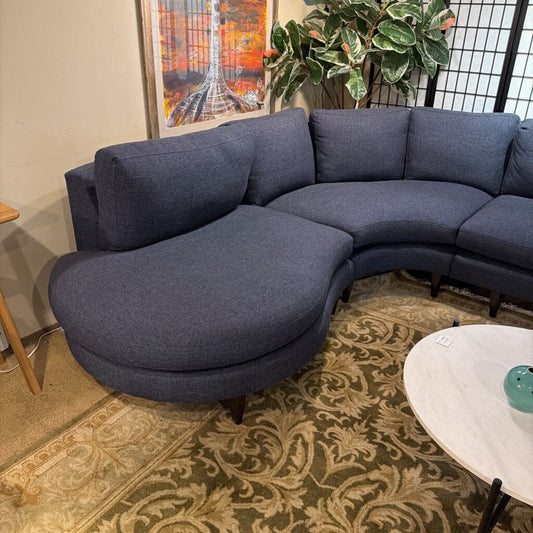 Blue sectional sofa in a room with a patterned rug, plant, and small table.