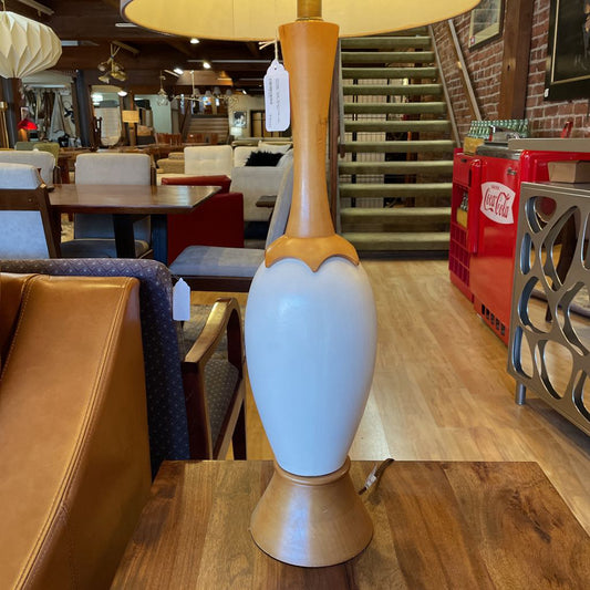 White lamp with wooden base on a table in a store setting