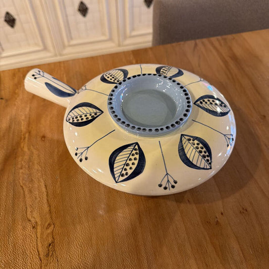 Ceramic bowl with leaf patterns on a wooden surface