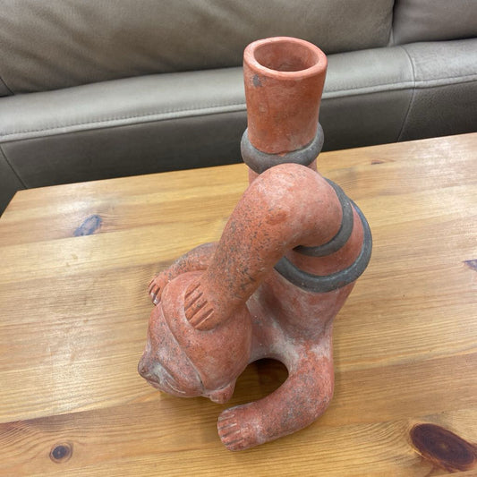 Ceramic sculpture of a bear on a wooden table with a gray couch in the background