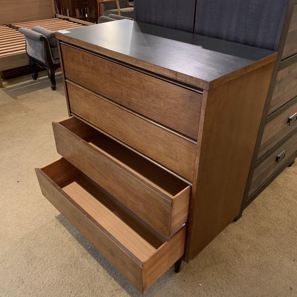 Wooden dresser with open drawer in a furniture store setting
