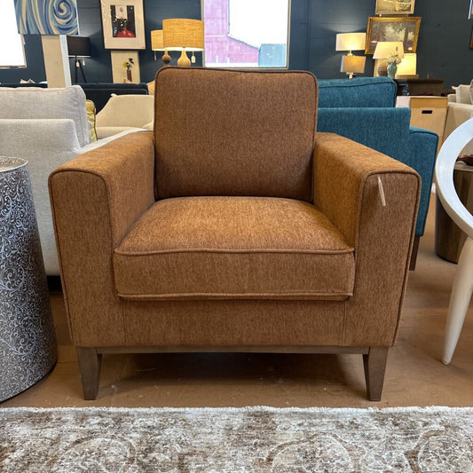 Brown armchair in a showroom with other furniture pieces.