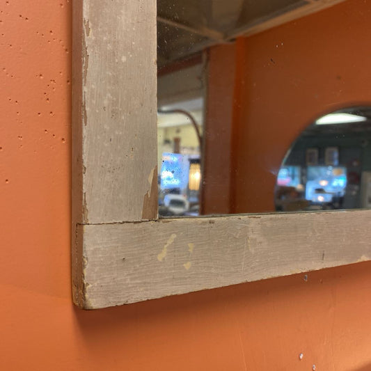 Wooden-framed mirror on an orange wall