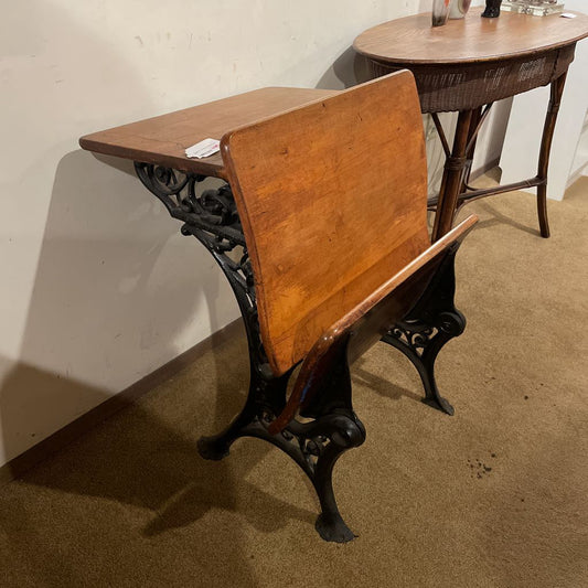 Vintage wooden desk with cast iron legs on a brown floor.