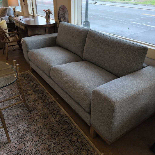 Gray sofa in a room with a rug and chairs