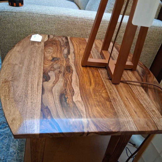 A small wooden side table with a curved triangular top, featuring a glossy natural grain and three slender tapered legs.