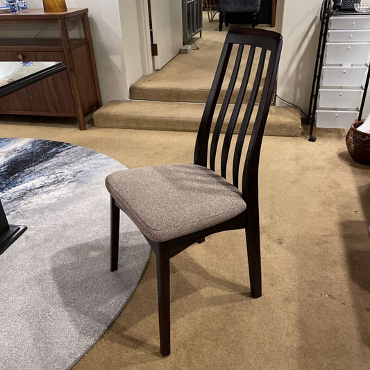 Wooden chair with a gray cushion on a carpeted floor in a store setting.