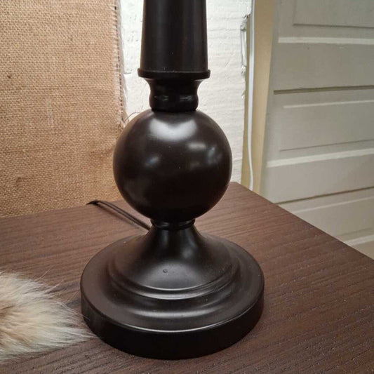 Dark brown candle holder on a wooden surface with a neutral background