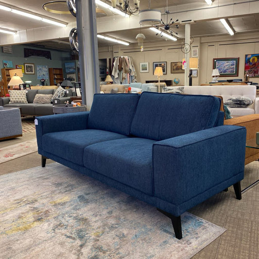 Blue sofa in a showroom with other furniture and decor items.
