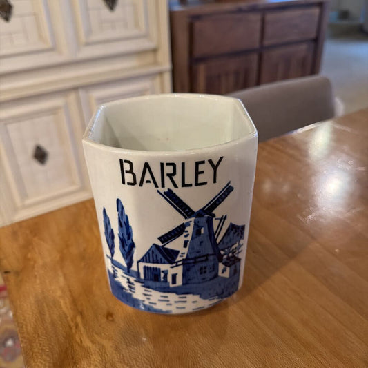 White mug with blue design and 'BARLEY' text on a wooden table