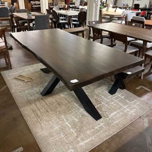 Large dark wooden dining table in a showroom setting with chairs and tables in the background.
