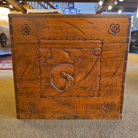 Wooden box with intricate carvings on a carpeted floor
