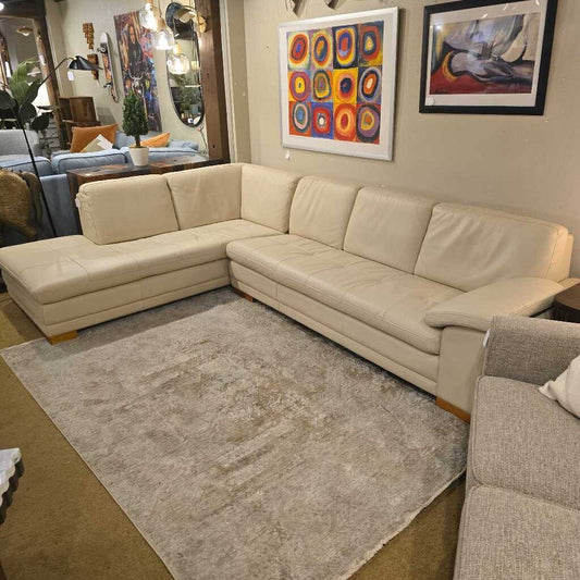 Beige sectional sofa in a living room with colorful abstract art on the wall.