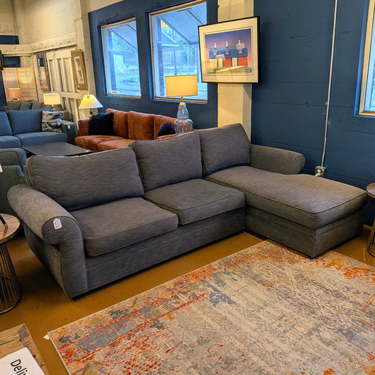 Gray sectional sofa in a room with blue walls and framed pictures.