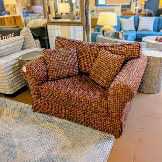 Patterned armchair in a furniture store setting with other seating options.