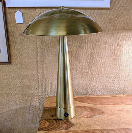 Gold table lamp on a wooden surface with a textured wall background