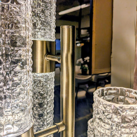 Close-up of a decorative glass and metal fixture with a blurred indoor background.