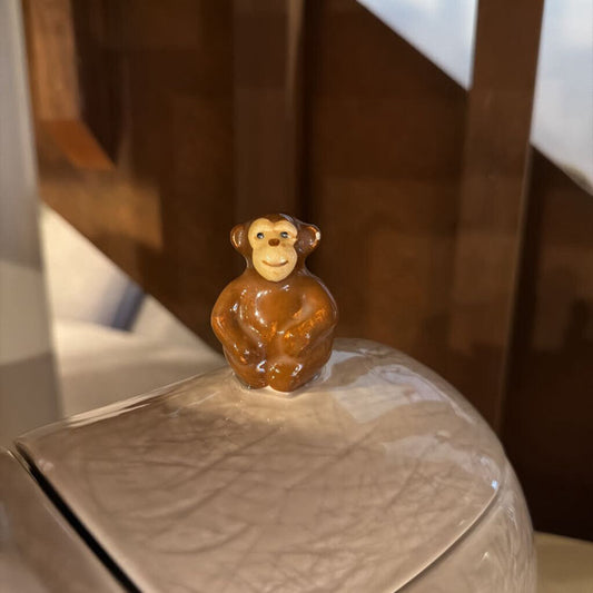 Small monkey figurine on a ceramic plate with a blurred background