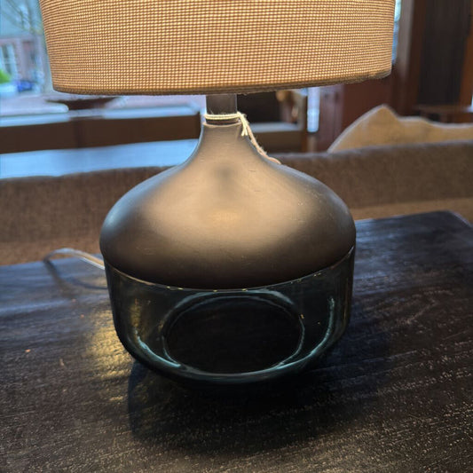 Table lamp with a textured beige shade on a dark surface