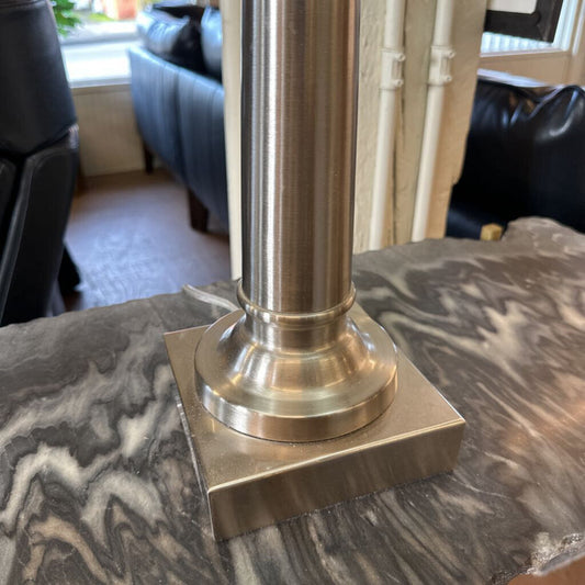 Metal pedestal on a marble surface with a blurred indoor background