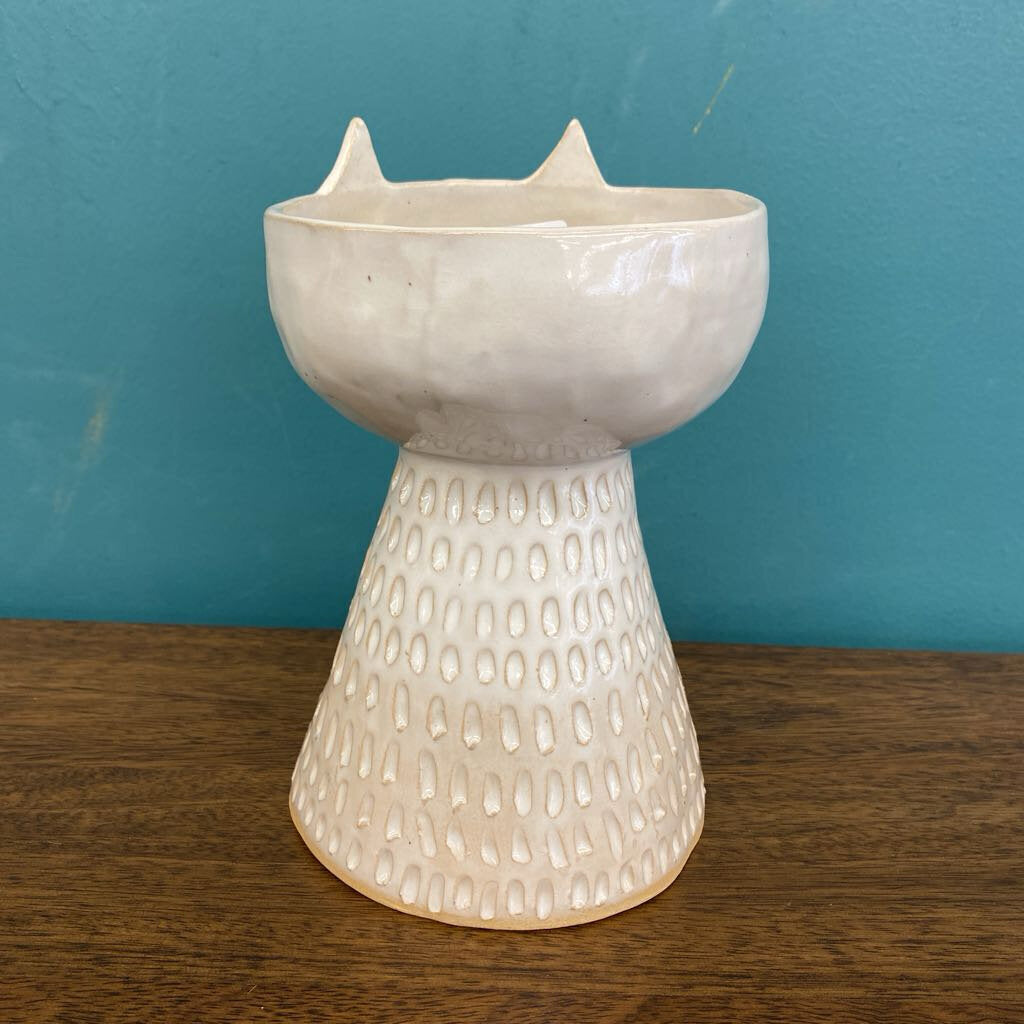 a white ceramic vase with the cat face and ears from the back