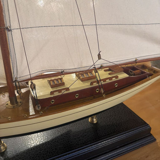 Model sailboat on a wooden stand with a white background