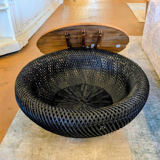 Black woven chair on a wooden floor with a white cabinet in the background