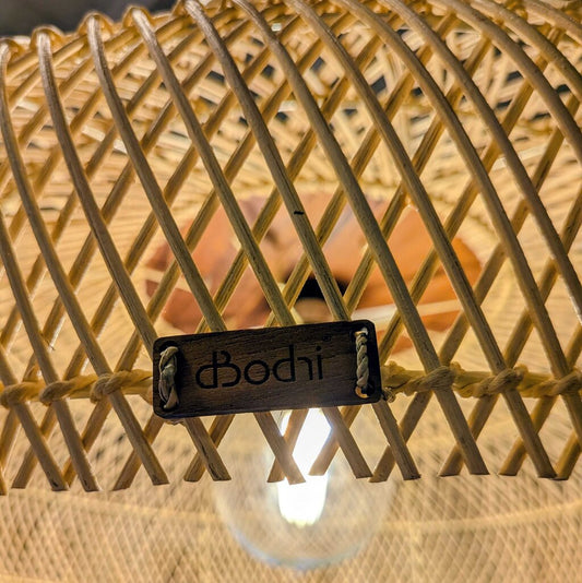 A large, bowl-shaped pendant light with a wide-weave rattan shade and a solid wood conical top, hanging in a rustic interior