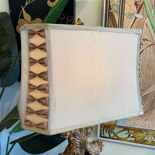 Decorative lamp with a patterned base and beige shade against a decorative wall.