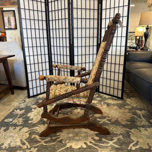 Wooden rocking chair in a living room with a screen and furniture.
