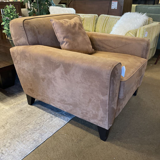 Brown upholstered chair with a pillow in a store setting
