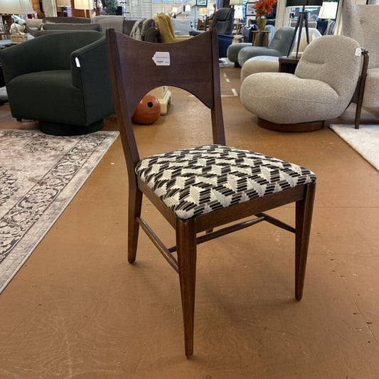 Wooden chair with a patterned cushion on a wooden floor in a furniture store.