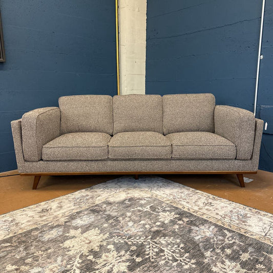 Gray sofa against a blue wall with a patterned rug on the floor.