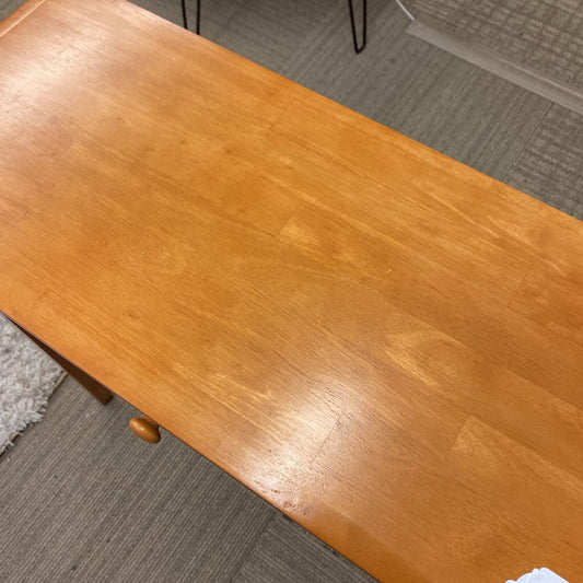 Wooden table with a worn surface on a gray carpeted floor