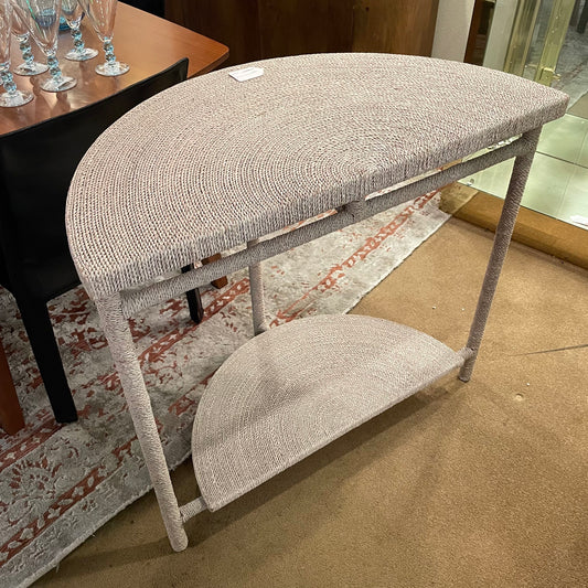 Half-moon shaped table with textured surface on a carpeted floor