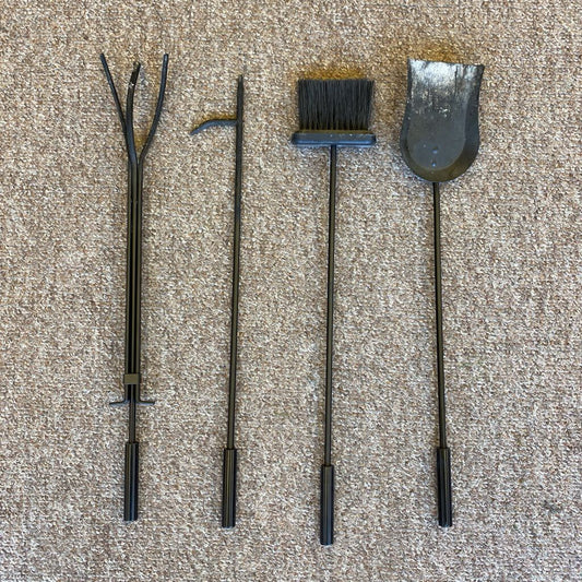 Set of four black fireplace tools on a beige carpet