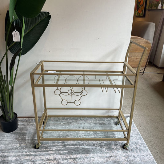 Gold bar cart with glass shelves in a room setting