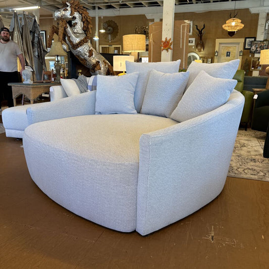 Round gray sofa with cushions in a showroom setting