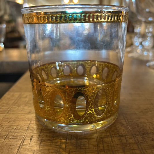 Glass with gold rim and intricate design on a wooden surface
