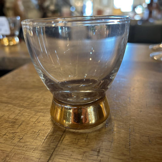 Clear glass with gold base on a wooden surface
