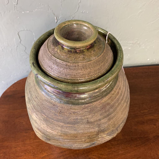 Stack of ceramic jars with green and brown glaze on a wooden surface.