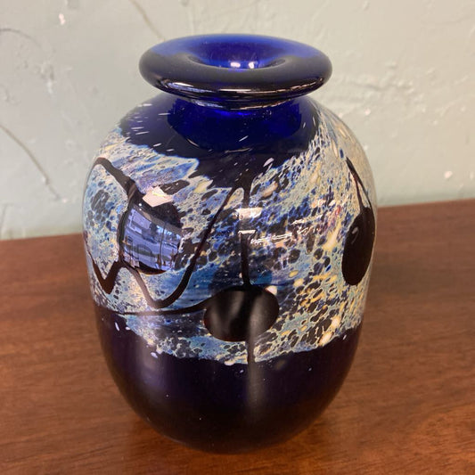 Decorative glass vase with blue and black patterns on a wooden surface