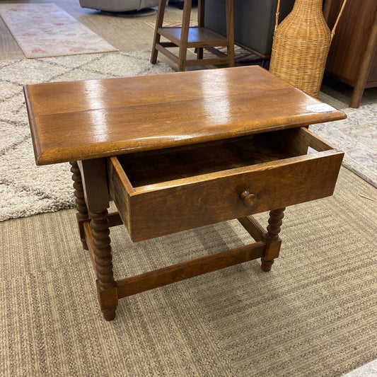 Wooden side table with a drawer on a carpeted floor