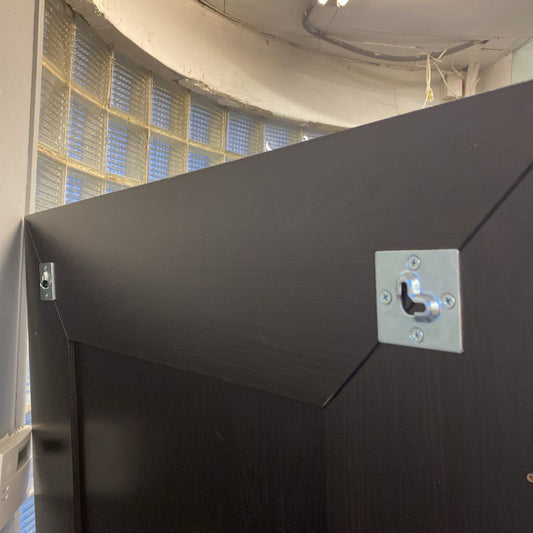 Black metal panel with a silver bracket on a wall with glass block windows.