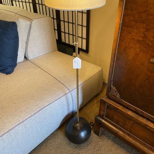 Floor lamp with a black base next to a beige sofa in a room.