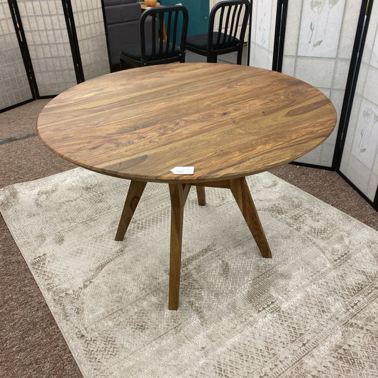 Wooden round table on a textured rug with a neutral background